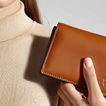 A sleek, elegant Loewe minimalist wallet, held gracefully in a person's hand, subtly complementing a contemporary, sophisticated outfit. The wallet's compact design and high-quality leather are highlighted, fitting seamlessly into a modern, minimalist lifestyle, perhaps near a chic micro bag or peeking from a pocket. Soft, natural lighting. Focus on fashion statement and understated luxury.