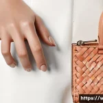 Home 13 보테가 베네타의 카드홀더와 미니 지갑 비교 - A close-up of a stylish woman's hands holding a peach-colored Bottega Veneta Intrecciato cardholder,...